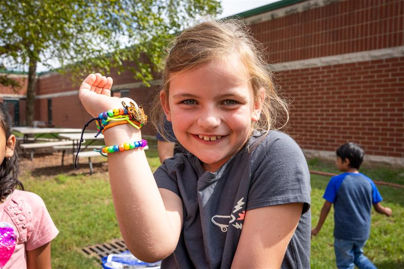 A girl holds a butterfly on her arm